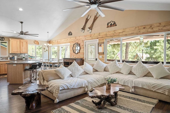 A spacious living area with a large sofa, wooden coffee table, and a ceiling fan.