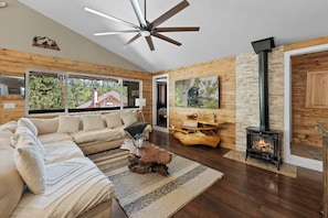 A modern living room with a sectional sofa, a fireplace, and a ceiling fan.