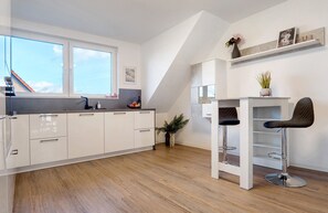 Eine moderne Küche mit weißen Schränken, einer Holz Arbeitsplatte und einer Bar mit Hockern.