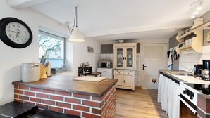 A kitchen with a brick island, white cabinets, a microwave, and a clock on the wall. - Apartment 'Room 24' with Terrace, Garden and Wi-Fi (Behrendorf)
