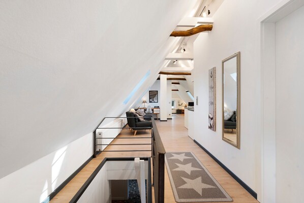 A modern interior with a staircase, a sofa, and a mirror.