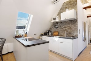 A modern kitchen with a stone accent wall, a built-in microwave, and a window overlooking the outside.