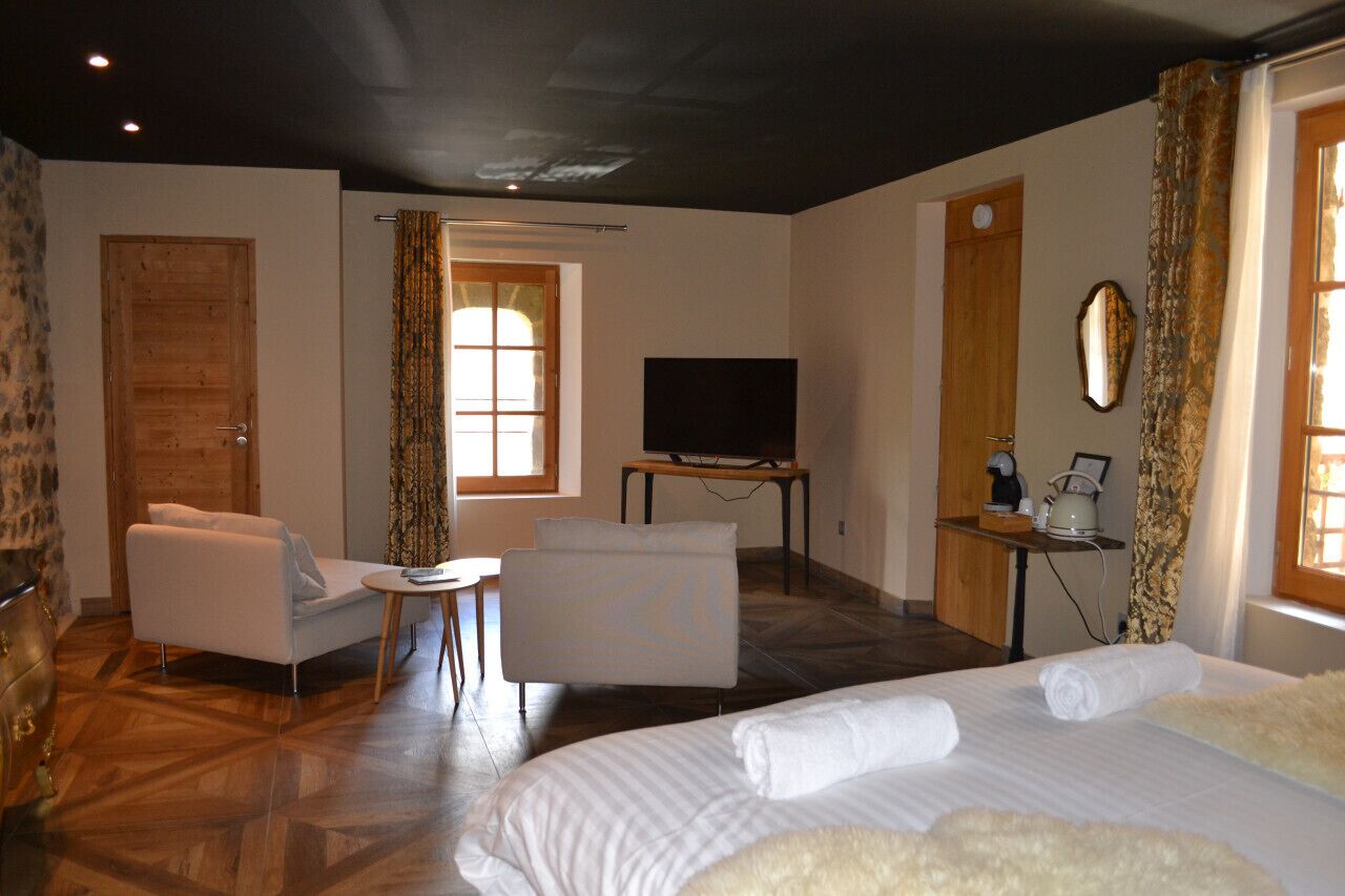 A hotel room with a bed, a sofa, a TV, and a desk with a computer.