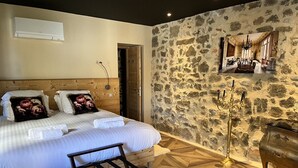 Une chambre avec un lit en bois, un mur en pierre et un lustre.