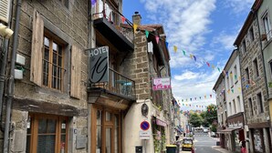 Hotel con un letrero, señal de no estacionamiento y vista de la calle con edificios y cielo despejado.