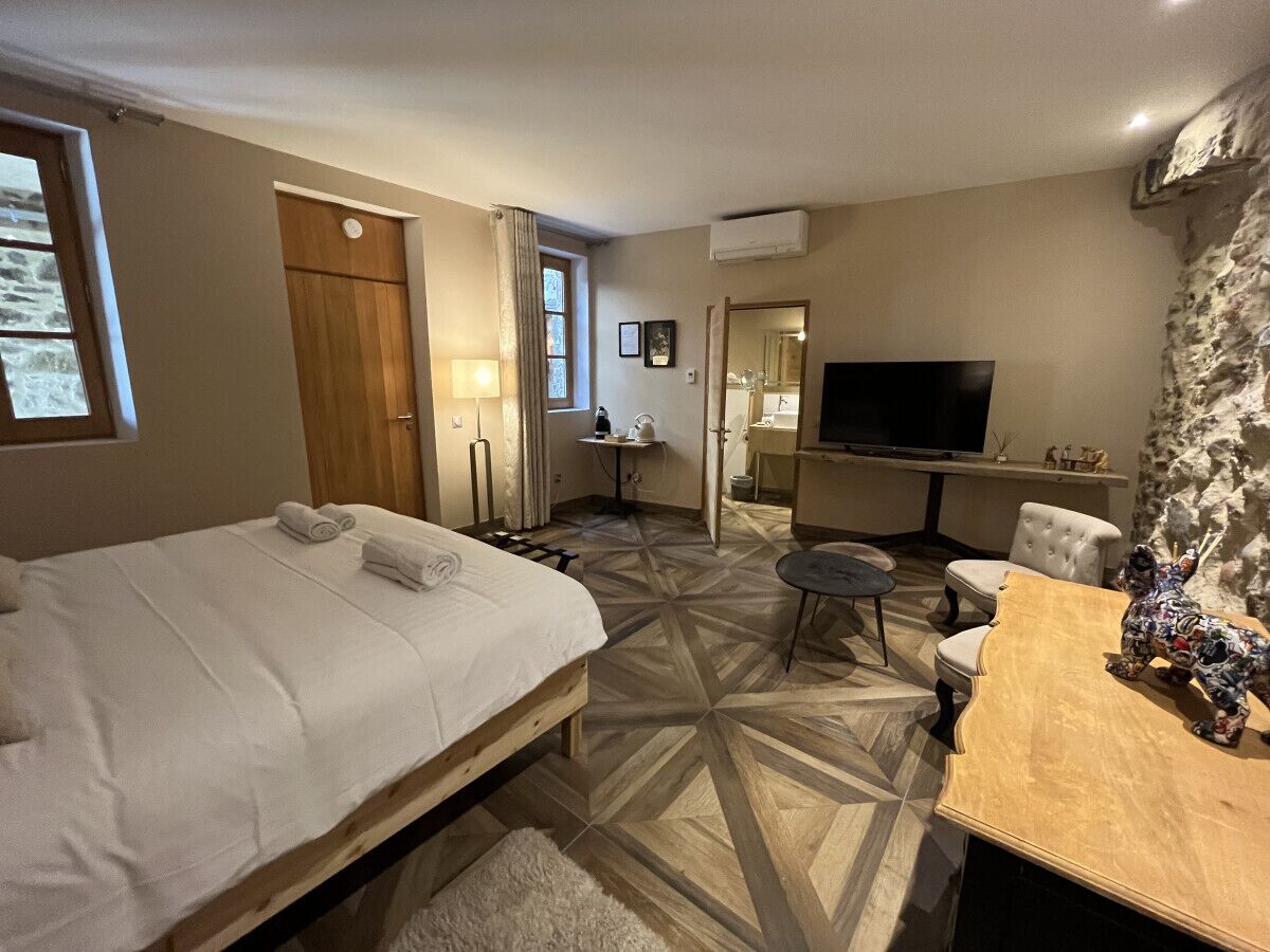 Een hotelkamer met een bed, een bureau, een stoel, een televisie en een stenen muur.