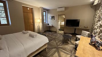 Een hotelkamer met een bed, een bureau, een stoel, een televisie en een stenen muur.