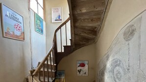 A staircase with wooden handrails and posters on the walls. - Le 19 - Suite 19 | 50m2 | Centre Historique | Clim (Langeac)