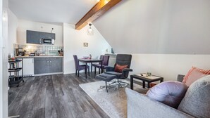 Una cocina moderna con comedor, un sofá gris y una viga de techo de madera.