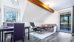Una sala de estar moderna con comedor, un conjunto de sofás y un ventanal con vistas.