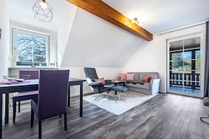 Una sala de estar moderna con comedor, un conjunto de sofás y un ventanal con vistas.