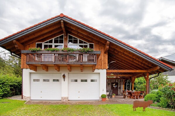 Un edificio di due piani con un balcone in legno, un portico coperto e un garage.