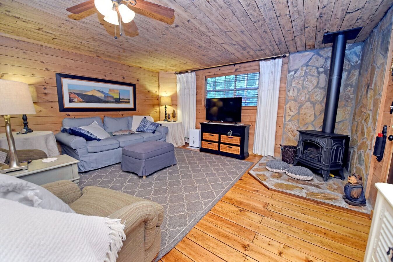 A cozy living room with a sofa, ottoman, and a fireplace.