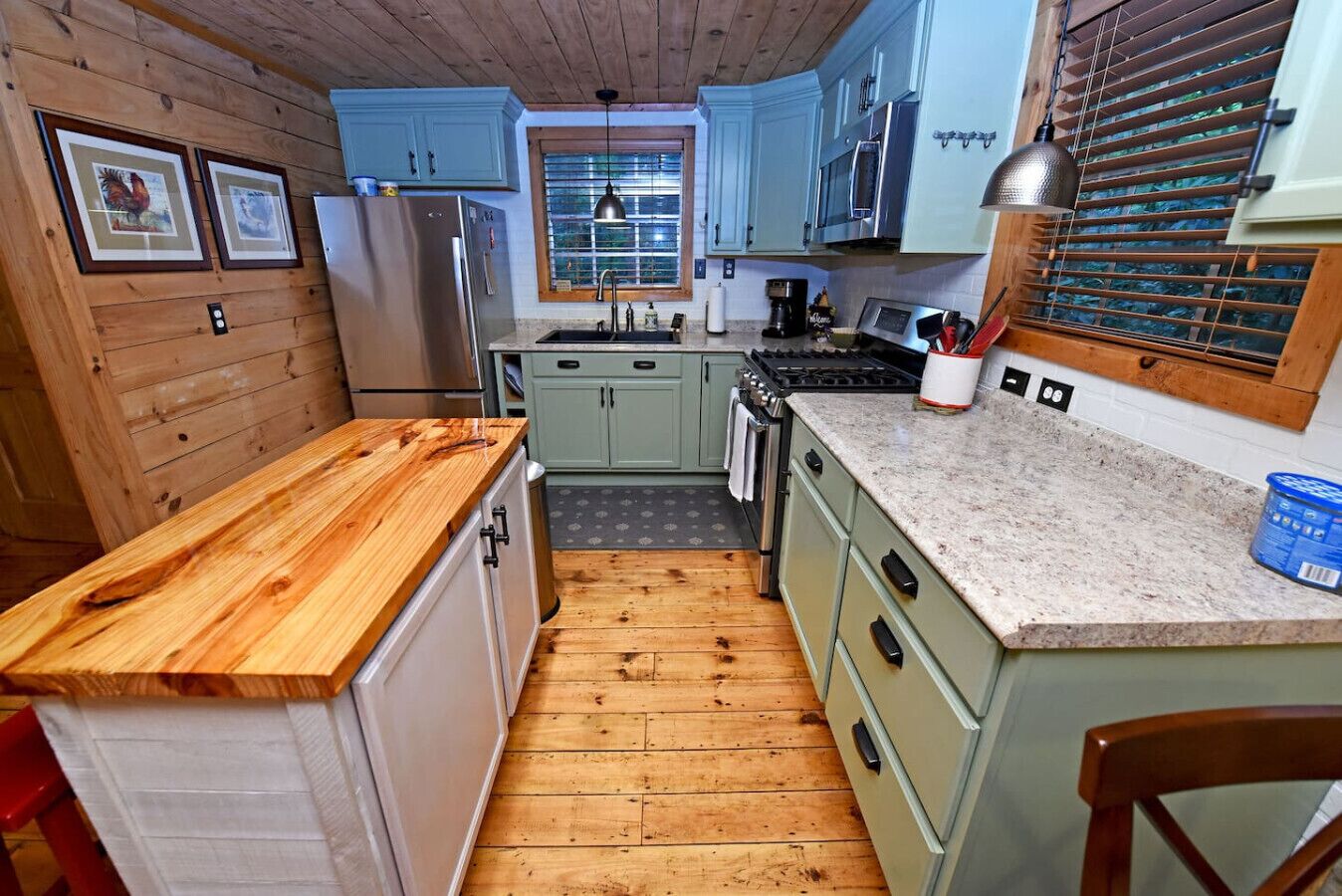A compact kitchen with wooden cabinets, a granite countertop, and a window with blinds.