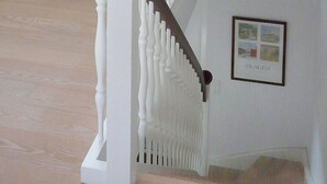 Een trap met witte spijlen en een ingelijst schilderij aan de muur.