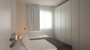 A bedroom with two beds, a window with curtains, and a wardrobe. - VIlla Olivo - MyHomeinComo (Blevio)