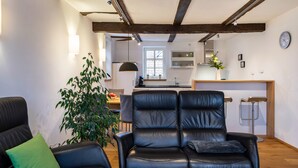 Una sala de estar moderna con un sofá de cuero, un cojín verde y una planta en maceta.