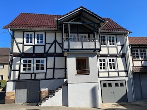 Un bâtiment à deux étages doté d’un balcon, d’un escalier et d’un garage.
