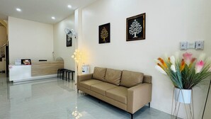 Ein Empfangsbereich mit einem beigefarbenen Sofa, einem Empfangstisch und zwei gerahmten Baum-Kunstwerken an der Wand.
