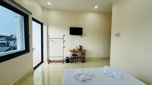 Ein Hotelzimmer mit einem Bett, einem Schreibtisch, einem Fernseher, einem Fenster und Blick auf Gebäude.
