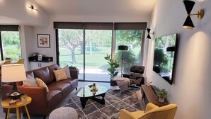 Una sala de estar moderna con un sofá, sillones, una mesa de centro y un televisor.