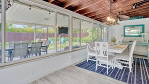 A spacious room with large windows, a wooden ceiling, and a dining area with white furniture. - Eagle`s Way: Heated Pool, Firepit & Sunroom Near BEACH! (North Palm Beach)
