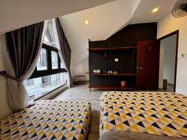 Una habitación con dos camas, una ventana con cortinas, una estantería con diversos objetos y una puerta.