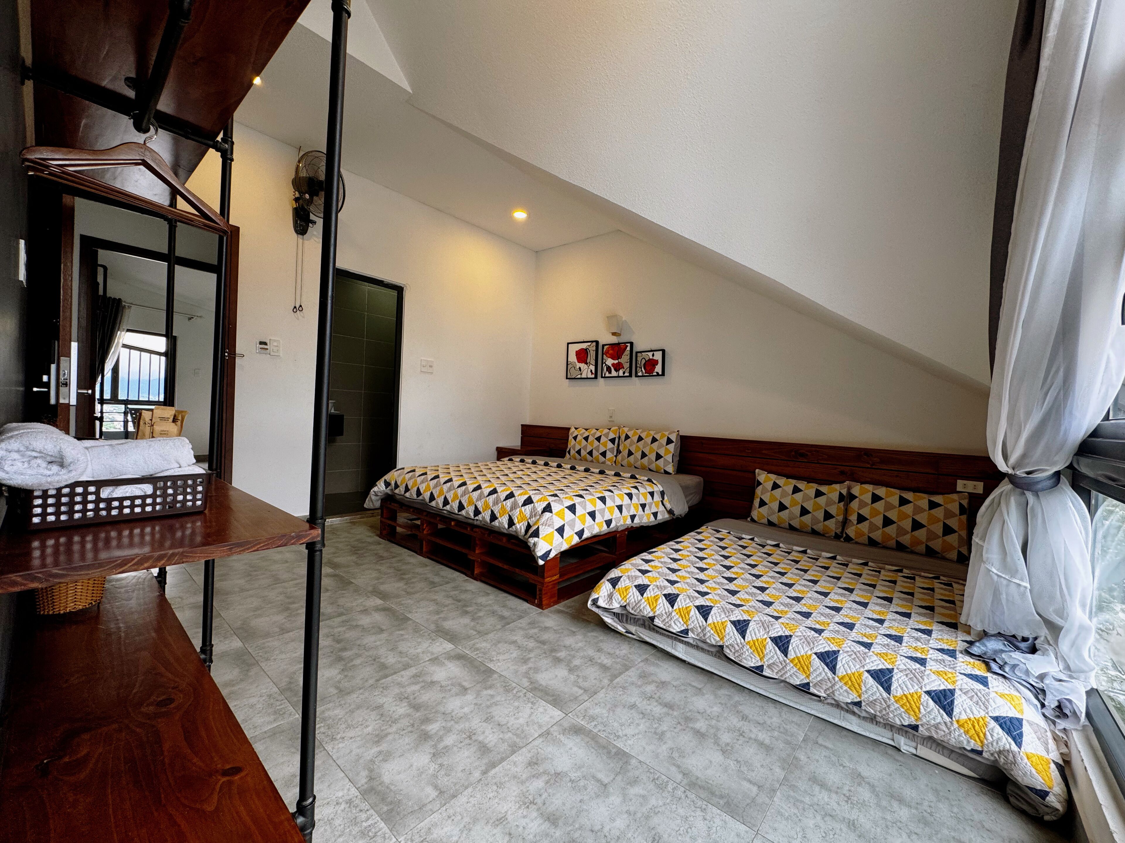 A bedroom with two beds, a wooden headboard, a mirror, and a window with curtains.