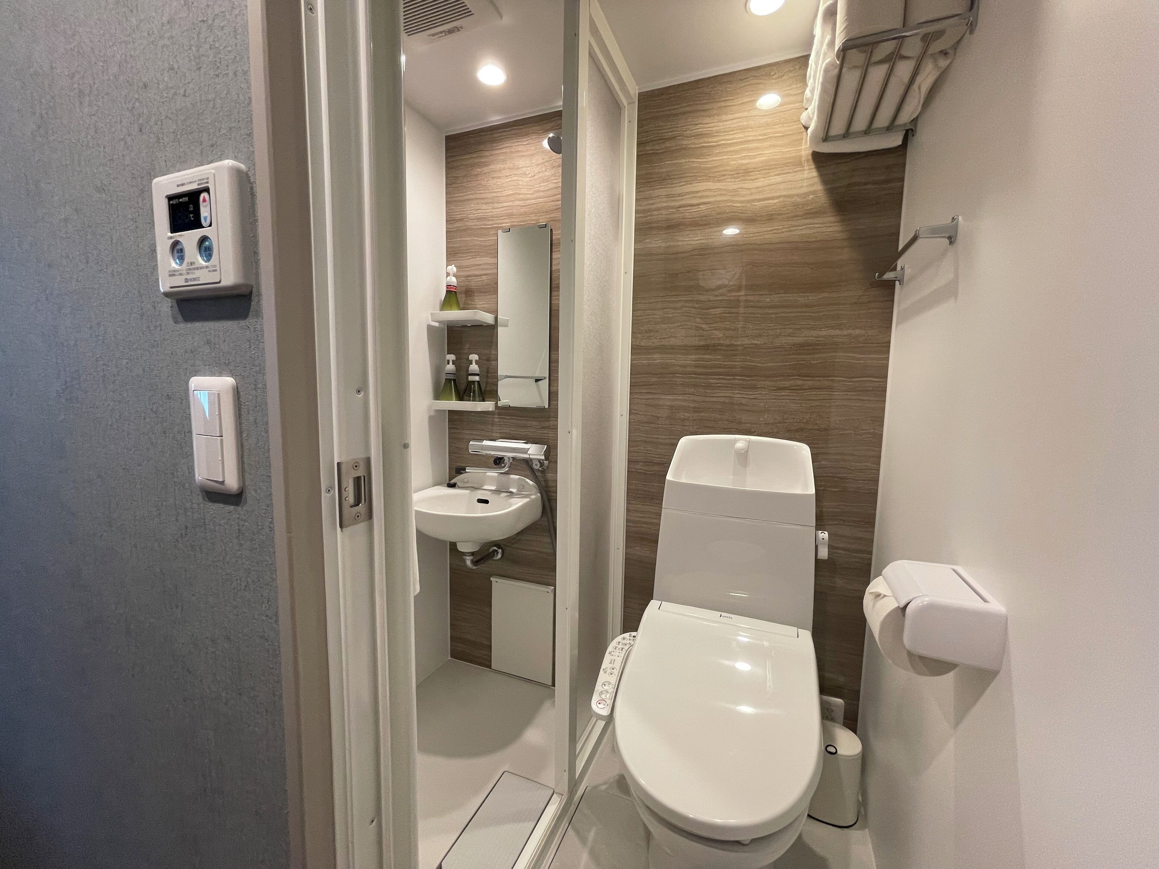 Une salle de bain moderne équipée de toilettes, d’un lavabo et d’un miroir encastré.