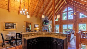 A spacious kitchen with granite countertops, dark cabinetry, and a stone fireplace. - One Day More (Banner Elk)