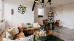 A living room with a sofa, coffee table, and dining area with chairs and a table. - Apartment 'Ferienwohnung Emma' with Mountain View and Wi-Fi (Güntersberge)