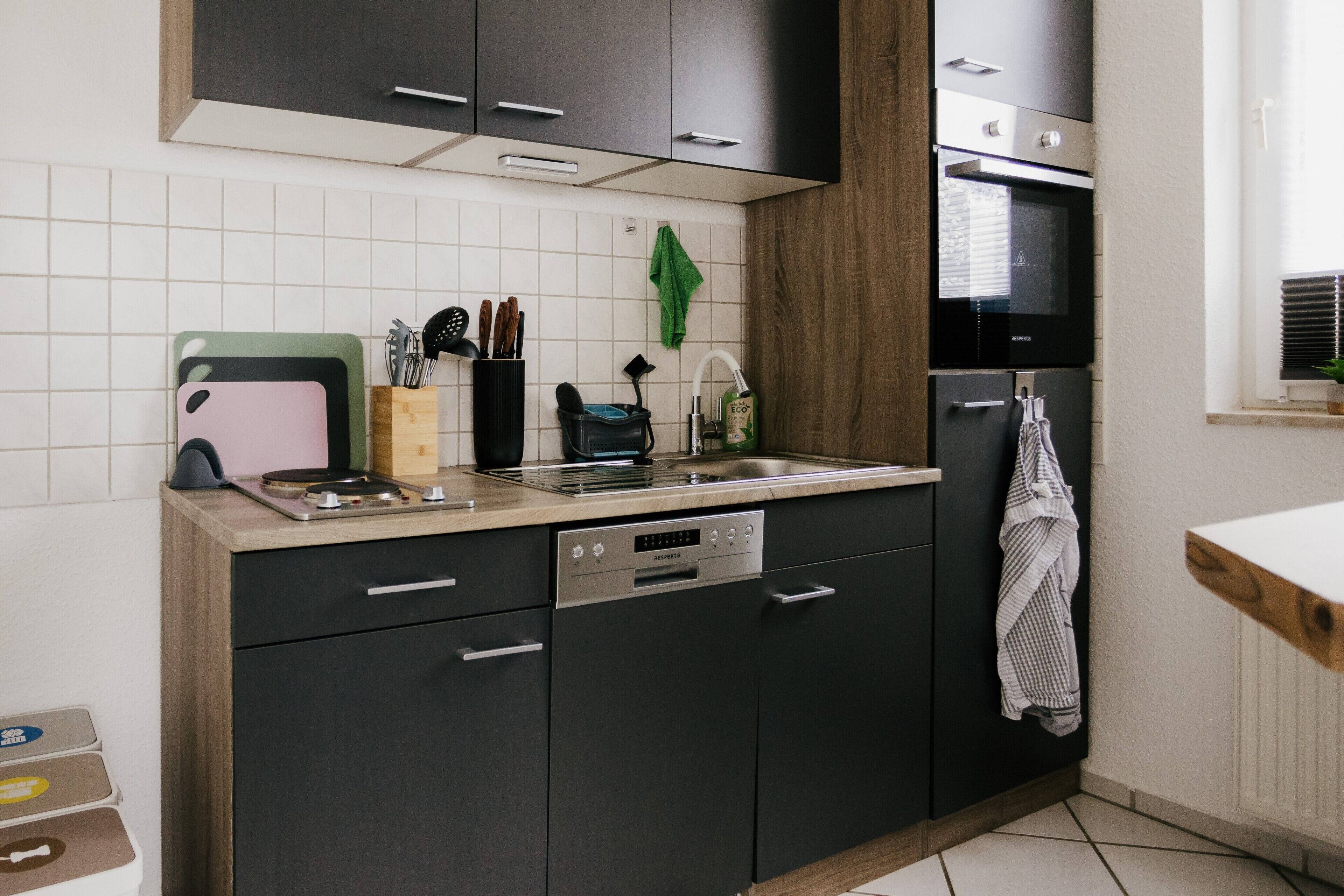 Een moderne keuken met donkere kasten, een inbouwoven en een vaatwasser.