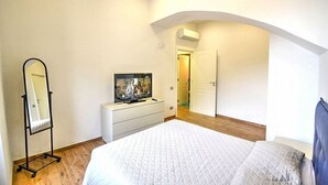 A bedroom with a bed, a dresser, a TV, and a mirror.