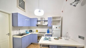 A compact kitchen with blue cabinets, a white countertop, and a small dining area.