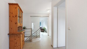Ein Korridor mit einem Holzschrank, einer Treppe und einer Tür zu einem anderen Raum.