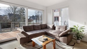 Ein modernes Wohnzimmer mit einem Ecksofa, einem Glastisch und einem Blumentopf.