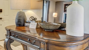 A wooden console table with a lamp, a decorative bowl, and a vase with green leaves. - Victory Mountain (Colorado Springs)
