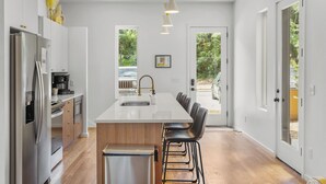 A modern kitchen with a central island, stainless steel appliances, and black bar stools. - Luxury Modern, Down Town Retreat, Pet Friendly (Chattanooga)