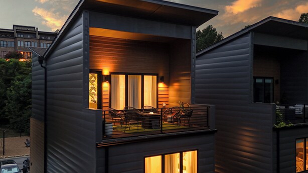 A modern two-story building with a balcony, large windows, and a visible interior with furniture. - Luxury Modern, Down Town Retreat, Pet Friendly (Chattanooga)