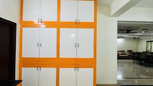 A room with a large wardrobe, a flat-screen TV, and a dining area with chairs and a table. - The Excellency Apartments (Hyderabad)