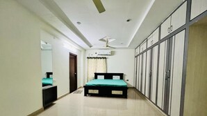 A hotel room with a bed, wardrobe, and ceiling fan. - The Excellency Apartments (Hyderabad)