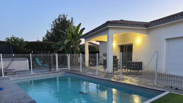 Ein Schwimmbecken mit Holzterrasse und eingezäunter Terrasse.