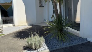 Ein modernes Haus mit Garage, ein kleiner Garten mit einer Palme und einem strahlend blauen Himmel.