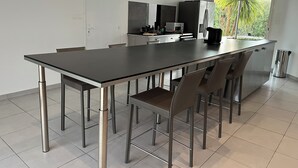 Eine moderne Küche mit einer zentralen Kochinsel, Edelstahlgeräten und Blick auf Grünfläche.