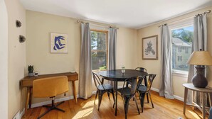 A dining area with a round table, four chairs, a small desk with a chair, and a lamp. - Cozy 2BR Loft, Stroll to Downtown A2 (Ann Arbor)