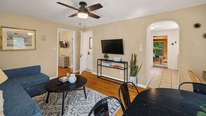 A living room with a sofa, coffee table, TV, and a ceiling fan. - Cozy 2BR Loft, Stroll to Downtown A2 (Ann Arbor)