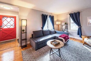 A living room with a grey sofa, a coffee table, and a red door.