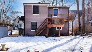 A two-story house with a wooden deck and a visible staircase leading to the upper floor. - Large 4BR Home, Walk to Downtown A2 (Ann Arbor)