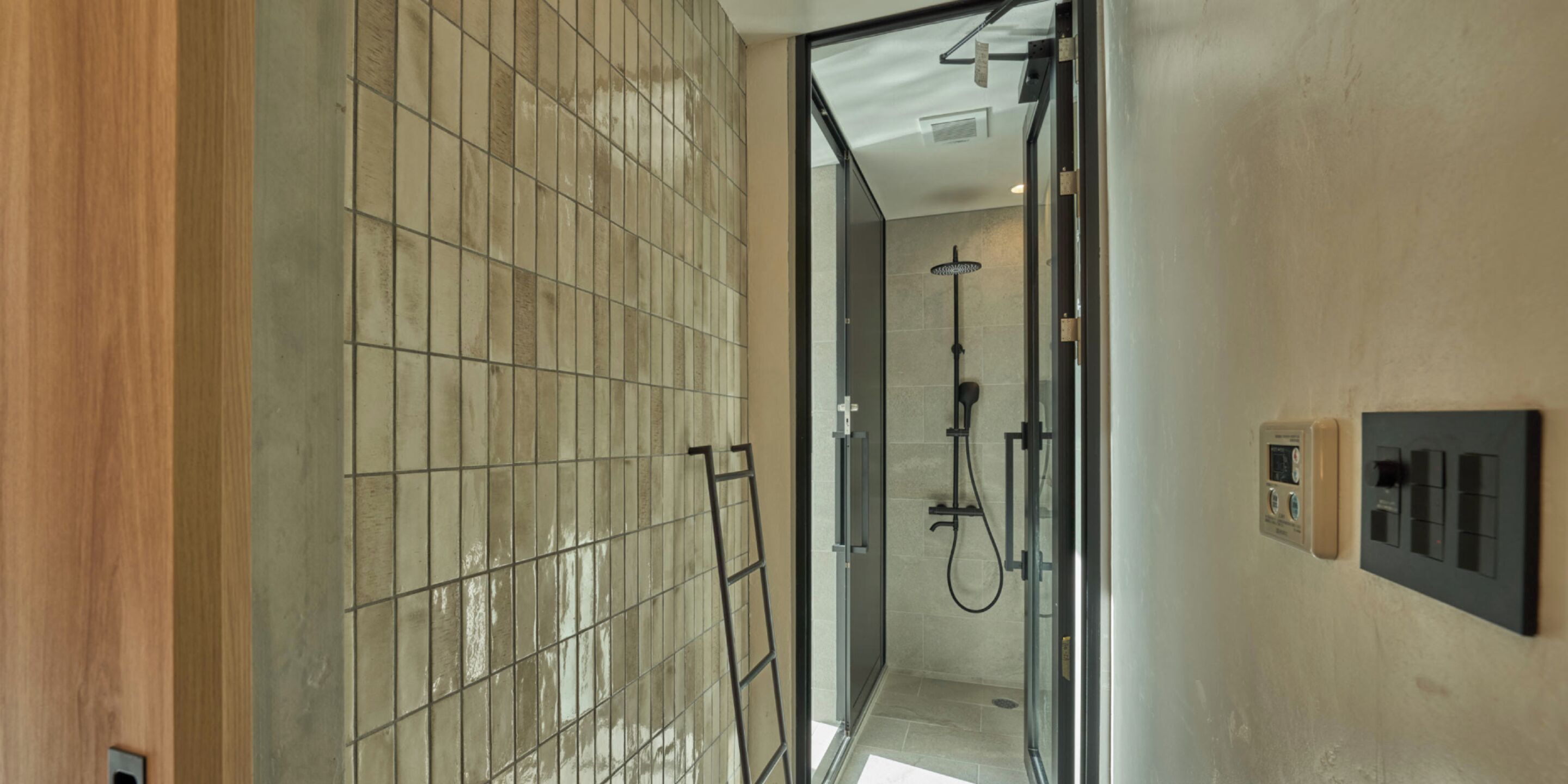 Ein modernes Badezimmer mit einer Duschkabine aus Glas, einer gefliesten Wand und einem Bedienfeld an der Wand.
