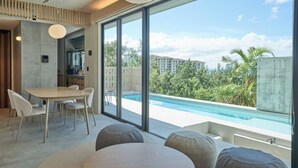 A modern living room with a dining area, large windows, and a pool view. - ima villa (Onna)